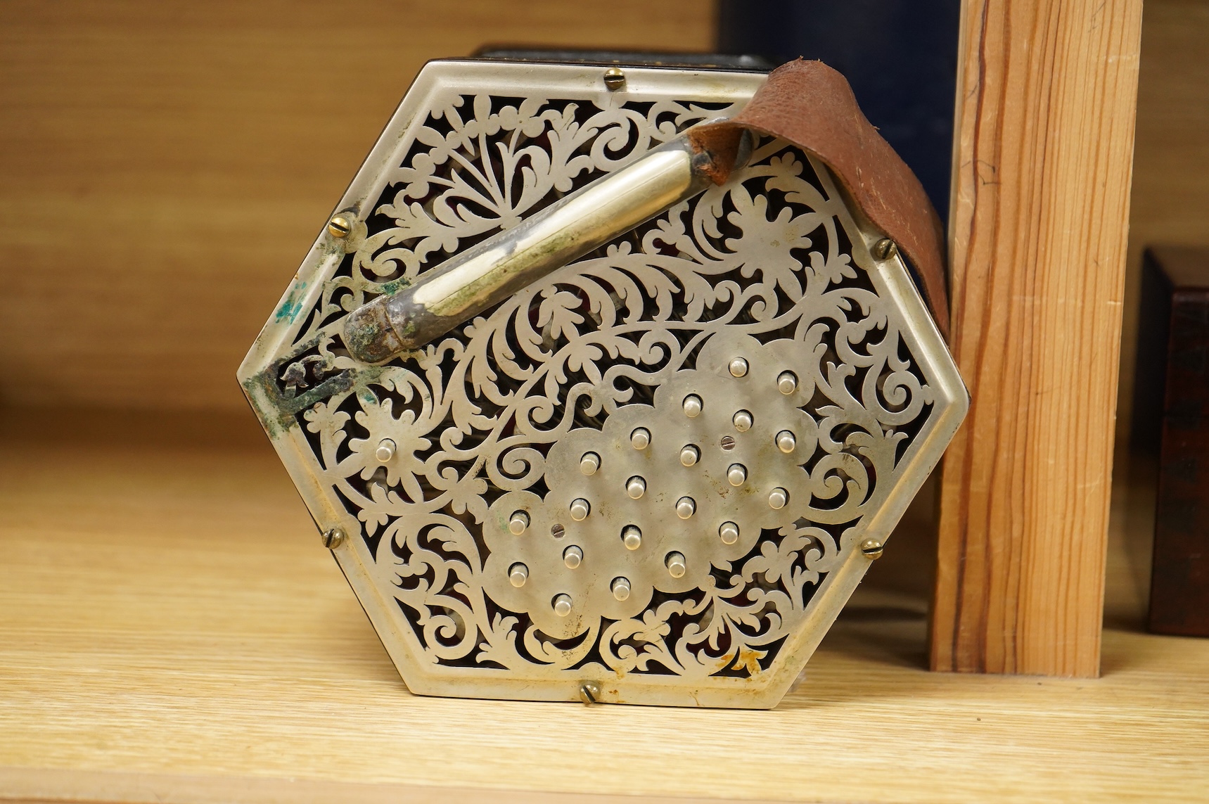 A Jeffries hexagonal concertina with pierced silvered metal ends, and gilt tooled leather bellows, maker’s mark stamped to the metal work on one end